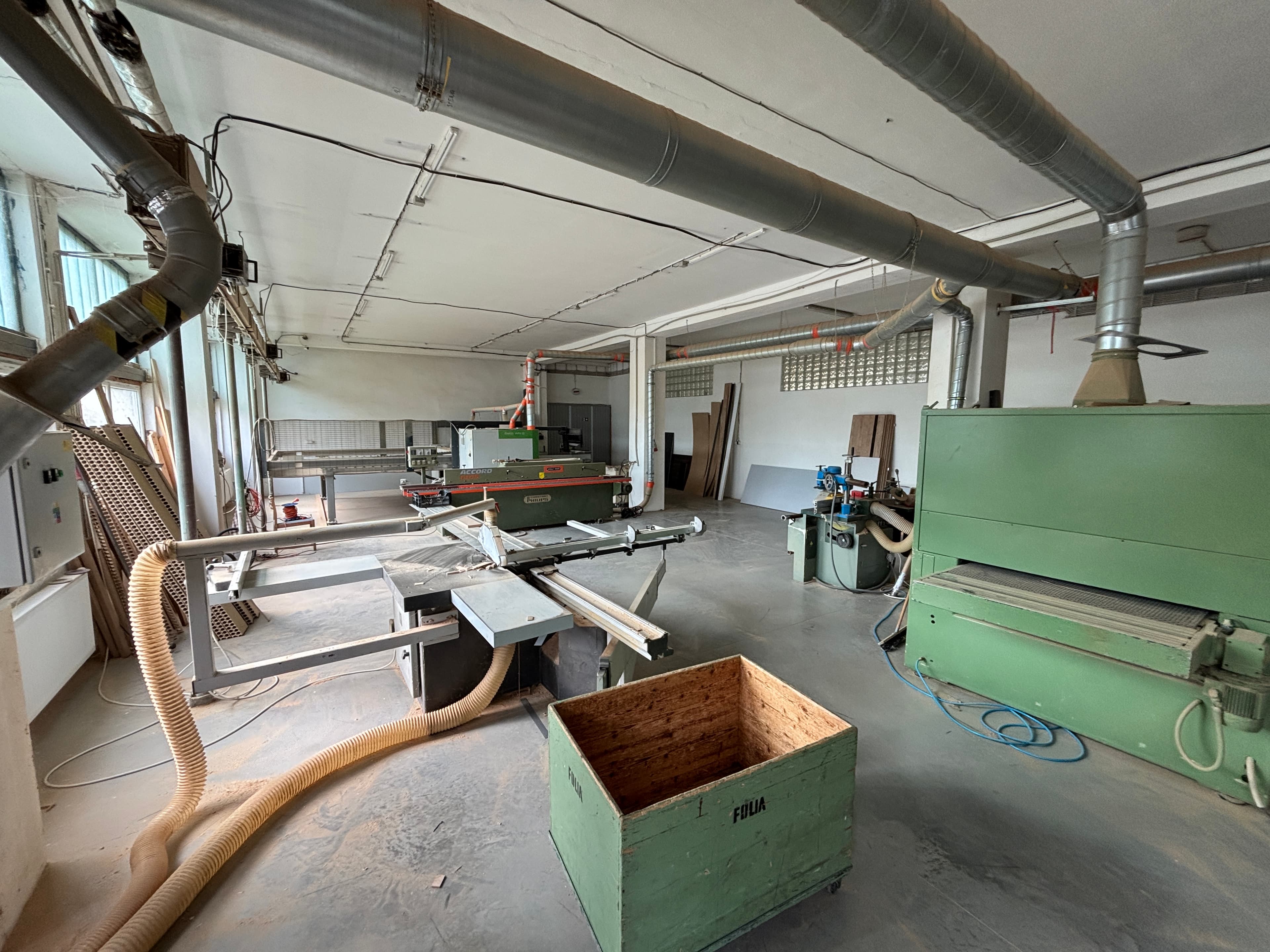 Wide view of the workshop with a wide-belt sander and overhead dust collection ductwork